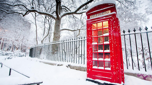 Телефонная будка красного цвета, в снегу на улице